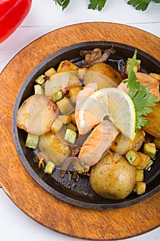 Fried salmon with potatoes on a sizzler