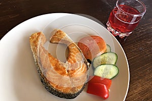 The fried salmon with sliced tomato and cucumber