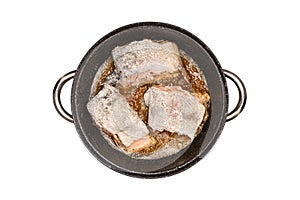 Fried salmon trout fillets in a frying pan in fat, flat top view, isolated on a white background with a clipping path.