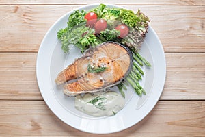 Fried salmon with vegetable on a round white plate