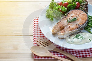 Fried salmon with vegetable on a round white plate