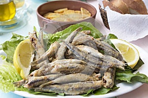 Fried sardines wth lemon pieces on a plate