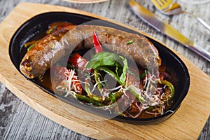 Fried sausage with stewed vegetables in a pan