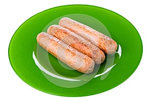 Fried sausages in green plate isolated on white