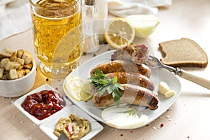 Fried sausages on a plate, ketchup, mustard, spices, beer mug