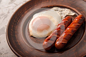 Fried sausages on a plate with scrambled eggs close-up and copy space. Boiled sausages and fried eggs for breakfast in a plate