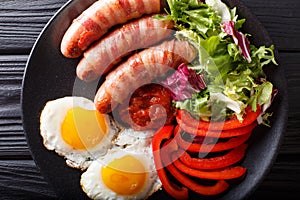 Fried sausages wrapped in bacon, eggs and fresh salad close-up.