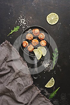 Fried scallops in a frying pan, dark stone background. Top view, overhead