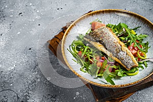 Fried sea bass fillet with vegetable salad, Dicentrarchus fish. Gray background. Top view. Copy space