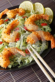 Fried shrimp with green pasta, chili, lime and sesame close-up o