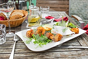 Fried shrimps, garlic dip, rucola salad, wine, bread on wooden table