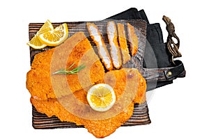 Fried sliced weiner schnitzel on a wooden board with herbs. Isolated, white background.