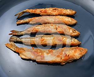 Fried smelt in breadcrumbs from flour on a plate. Close-up view