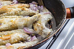 Fried smelt fish lies on a frying pan