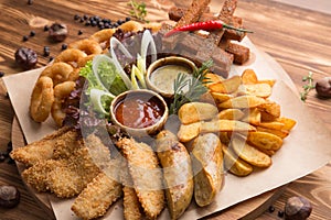 fried snack for beer. Large plate of beer snacks: croutons  fried onion rings in batter  french fries  potato wedges. Hot sauce