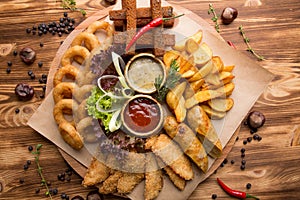 fried snack for beer. Large plate of beer snacks: croutons  fried onion rings in batter  french fries  potato wedges. Hot sauce