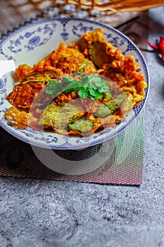 Fried Solanum melongena with Egg in a green dish on the table with garlic, dried chilli