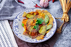 Fried Solanum melongena with Egg in a green dish on the table with garlic, dried chilli