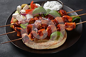 Fried souvlaki, greek salad and tzatziki on wooden table.