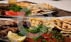 .Fried souvlaki, traditional lamp kebab with fresh salad and sauce in plate on wicker surface