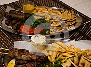 .Fried souvlaki, traditional lamp kebab with fresh salad and sauce in plate on wicker surface