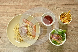 Fried spicy spaghetti carbonara topping bacon with pork sausage on plate and French fries couple salad
