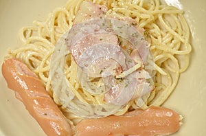 Fried spicy spaghetti carbonara topping bacon with pork sausage on plate and French fries couple salad