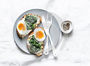 Fried spinach, labne and boiled eggs sandwiches - delicious healthy breakfast or snack on a light background