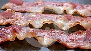 Fried strips of bacon are roasting of the stone surface