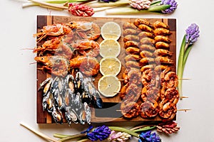 Fried tails of langoustines and fried mussels with sauce and fried shrimps and sliced lemon on wooden cutting board with card and