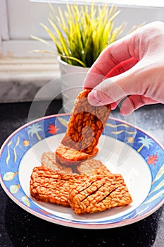 Fried tempeh / tempe held by hand, Indonesians usually eat these savory snacks using their hand. Tempeh a traditional Indonesian s