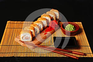 Fried tempura sushi rolls set on wooden plate on dark background. Japanese traditional fusion food style, restaurant