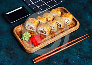 Fried tempura sushi rolls set on wooden plate on dark background. Japanese traditional fusion food style, restaurant