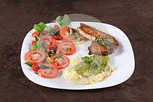 fried tilapia fish filet served on plate with tomato salad and mashed potatoes with herb pesto