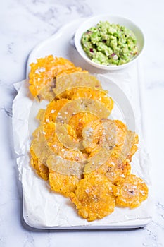 Fried tostones, green plantains, bananas with guacamole sauce photo