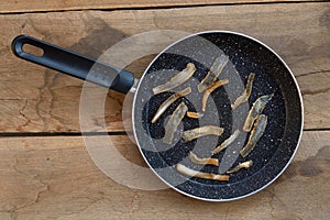 Fried transparent bacon strips on black granit pan, wooden board