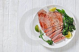 Fried tuna steak with boiled broccolini and lime