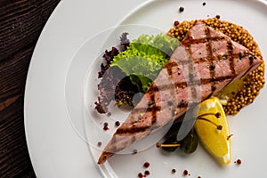 Fried Tuna Steak on Round White Plate with Seasoning and Fresh G