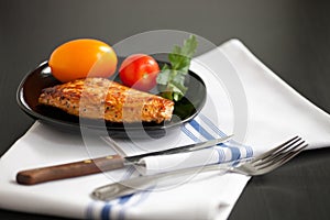 Fried  turkey steak on a black plate with tomatoes