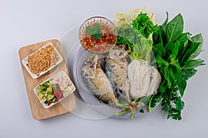 Fried two short bodied mackerel fishes and vegetable on white plate on black table