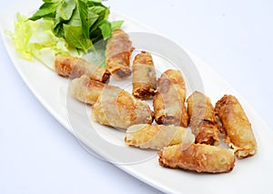 Fried Vietnamese spring rolls with herbs on white dish