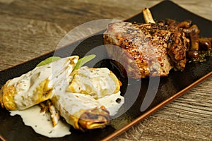 Fried vile ribs with mushrooms and pasta with blue cheese sauce on a wooden table