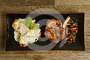 Fried vile ribs with mushrooms and pasta with blue cheese sauce on a wooden table