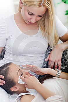 Friend comforting her crying friend at home on the couch