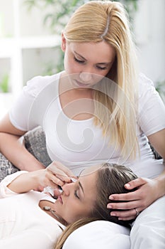 Friend comforting her crying friend at home on the couch