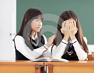 Friend comforting to sad student in classroom