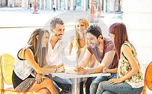 Friend group sitting at restaurant bar having fun with tablet pc - Connected community of young students people using portable photo