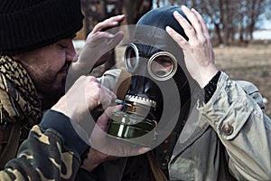 A friend helps his buddy to take on the gas mask for the mission