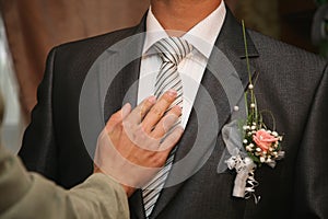 Friend straightens his tie groom