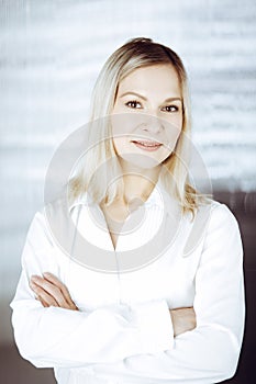 Friendly adult business woman standing straight. Business headshot or portrait in sunny office